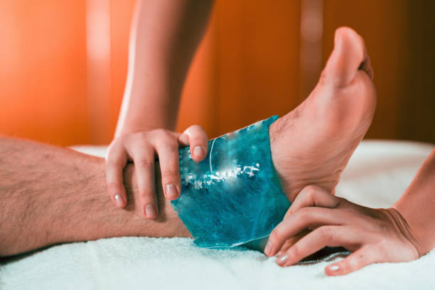 Holding the blue ice pack on on the painful ankle joint